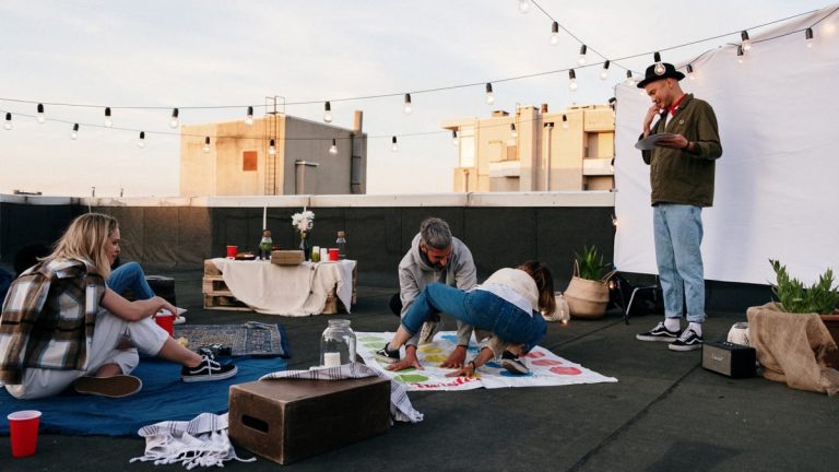 Friends enjoying a fun game night on a rooftop with lights and snacks.