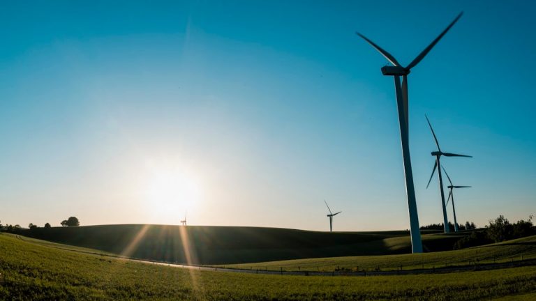 the sun is setting behind a row of windmills